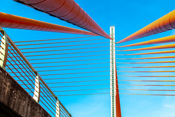 Fototapeta premium Modern architectural bridge design with vibrant cables against blue sky