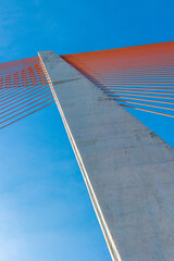 Modern suspension bridge with orange cables against clear blue sky