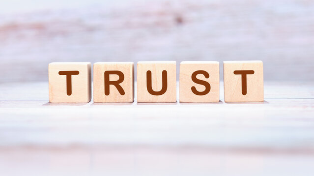 The concept word TRUST is assembled from wooden cubes. Investment based on trust concept