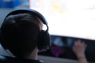 A person is wearing a pair of headphones as they are intensely engaged in playing a video game on their computer system