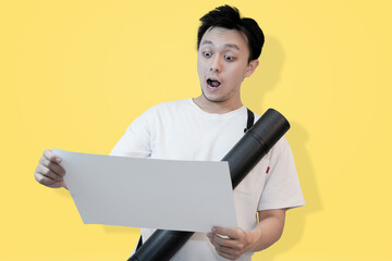 young asian man surprisingly reading documents or project paper on isolated pink background