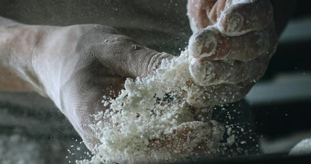 Cinematic Super slow motion close up of professional artisan baker chef sprinkles flour on raw loaf of dough while making homemade bread, pasta or pizza on rustic wooden table in traditional bakery ki - Powered by Adobe