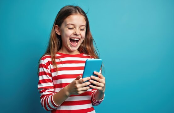Happy young girl uses smartphone. Woman excited with success, good news. Cheerful female person holds cell phone looking at screen smiling on bright blue background. Joyful emotion. Mobile tech