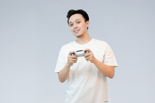 young asian man happily playing video games with controller in studio background