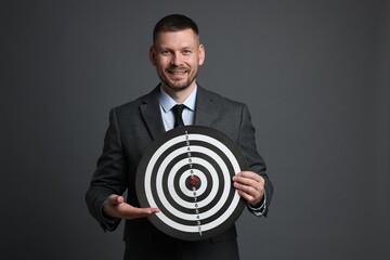 Targeting. Man with dart board and arrow on grey background