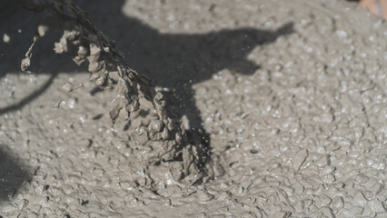 Close-up of wet concrete being poured, showing rich texture and motion in construction work. Perfect for themes of raw material, industrial process, and real-world building scenes.