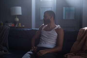 African American man feeling uncertain of emotional disorder in bedroom
