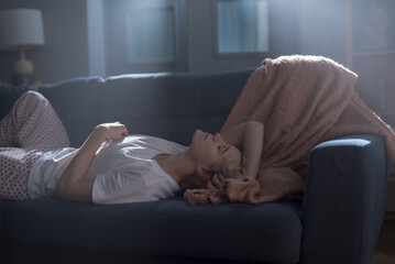 Young woman lies on couch appearing lost in thought