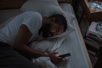 African American male with insomnia scrolls social media pages losing ability to rest