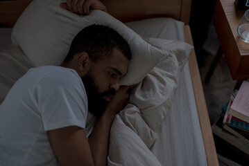 African American man suffers from sleeping disorder in bedroom