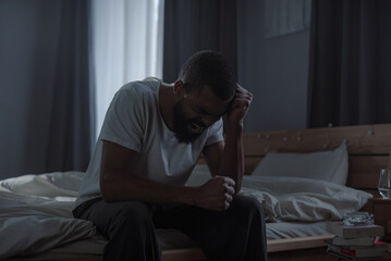 Fototapeta premium Hopeless African American man yells feeling strong stress in bedroom