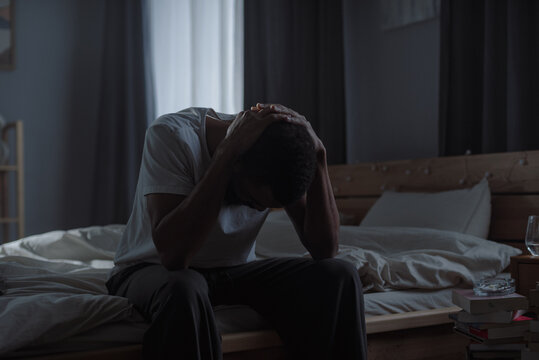 African American man holds head in hands suggesting state of emotional distress - Powered by Adobe