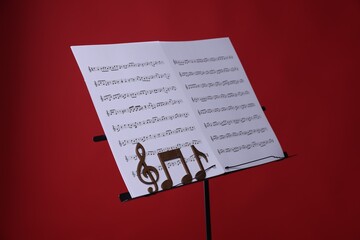 Stand with music sheets and wooden notes on red background, closeup