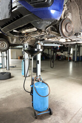 Dirty old motor oil dripping from car engine into container in workshop