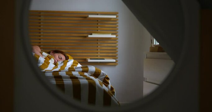 A woman reflected in a mirror is in her bedroom bed sleeping in the morning.