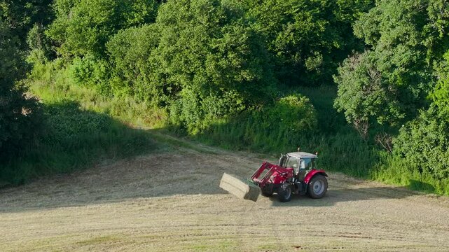 Farmer harvests hay with a tractor in the fields of Devon, Torquay, England