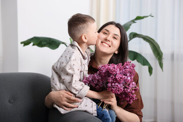 Mother and her son with bouquet of lilac flowers at home