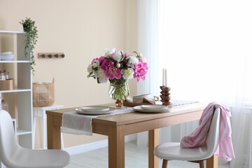 Beautiful table setting with bouquet of peonies in dining room. Interior design