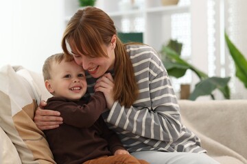 Happy mother spending time together with her son on sofa at home
