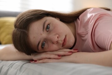 Depressed teenage girl on bed at home