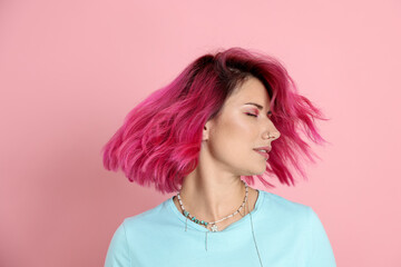 Beautiful woman with bright dyed hair shaking head on pink background