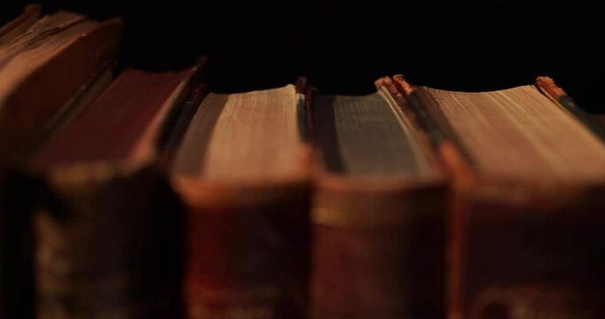 Stack of old antique books in a ray of light. Close-up view, slider macro 4K video.