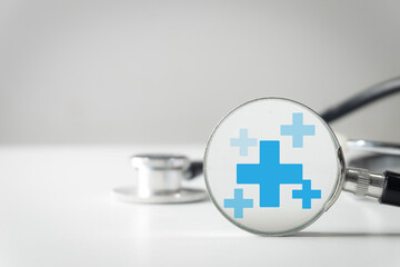 Close-up of a stethoscope reflecting plus or cross icons on white background with copyspace idea...