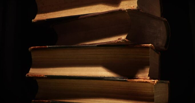 Stack of old antique books in a ray of light. Close-up view, slider macro 4K video.