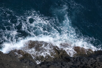 Fototapeta premium ocean waves crashing on volcanic rocks - top view
