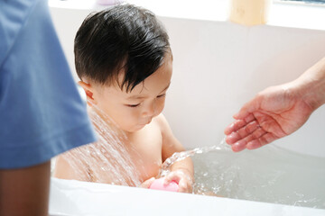 A cute little child is smiling happily while taking a bath.