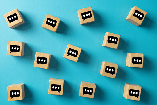 Wooden blocks with chat bubble icons scattered on a blue surface concept for socia media,online communication,community discussion,digital world,business network.