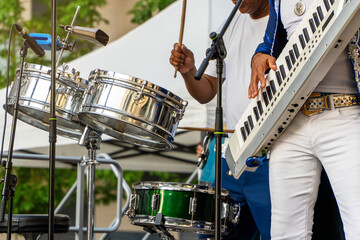 Summer music festival at the park with band playing drums and keytar on the stage