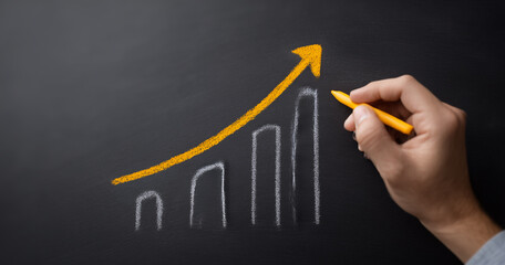 Hand drawing upward trend graph on blackboard