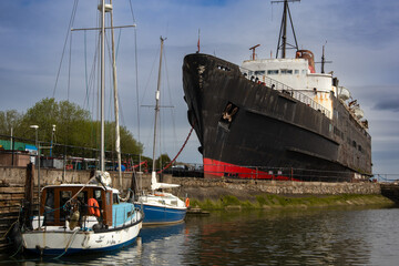 Dramatic low-angle shot of the TSS Duke of Lancaster, a beached and weathered ship with a black...