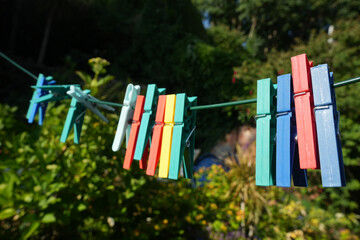 Colorful plastic clothespins hanging on a washing line in a lush garden on a sunny day in England