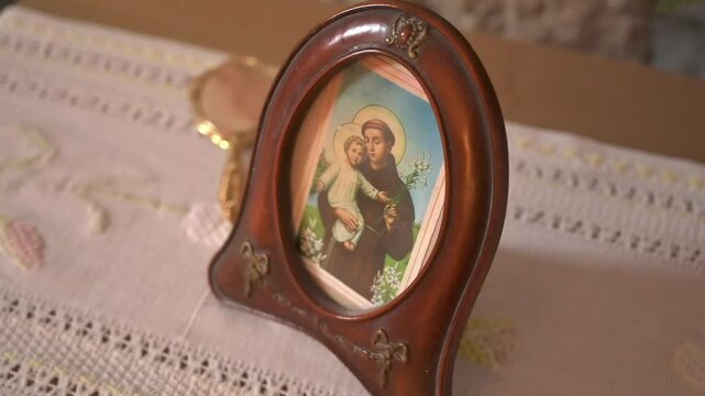 Framed icon of Saint Anthony with Child Jesus on embroidered vintage linen in traditional Mediterranean interior