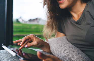 Close-up of woman’s hand using stylus on digital tablet, sitting on pillow with rice field...