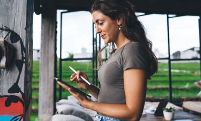 Stylish young woman standing with tablet and stylus, working remotely from eco coworking space...