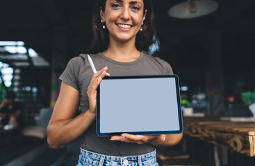 Confident female entrepreneur smiling and presenting blank digital tablet with stylus, ideal for...