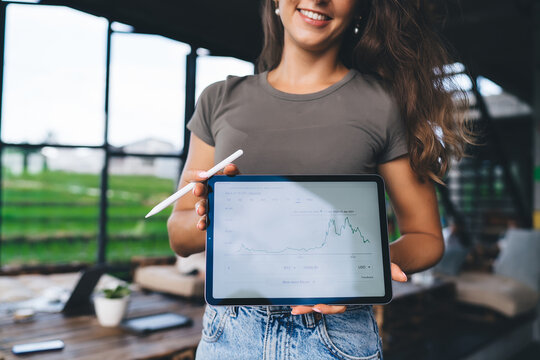 Smiling young woman holding tablet with cryptocurrency chart in outdoor workspace, representing modern investing, fintech, and remote financial analysis with digital tools