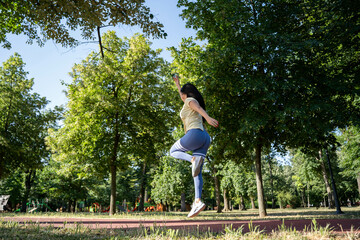 Beautiful woman doing jumps while running on a track in the park during a sunny morning