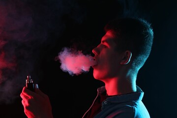 Man using electronic smoking device in neon lights on black background