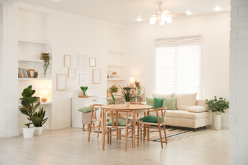 Stylish dining table with chairs and comfortable sofa in room. Interior design