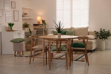 Stylish dining table with chairs and comfortable sofa in room. Interior design