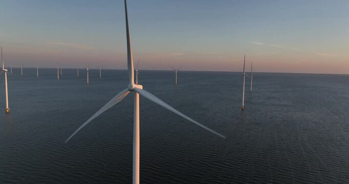 Scenic drone view of a rotating wind farm in a water body on the Afsluitdijk, under a cloudy sky