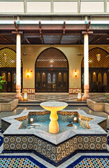 Interior of Ash Shaliheen Mosque, in Bandar Seri Begawan, Brunei, highlights intricate designs, with a stunning fountain at its center surrounded by vibrant mosaics and lush greenery