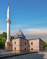 Unique architecture of Shems-i Tebrizi Mosque and Tomb in Konya, Turkey, surrounded by lush greenery and a clear blue sky, reflecting its historical significance and beauty