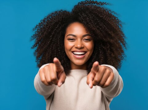Excited woman smiles and points at viewer directly