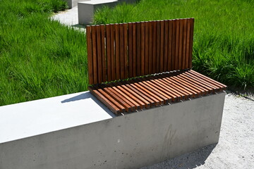ławka drewniana na betonowym podłożu w tle trawnik
