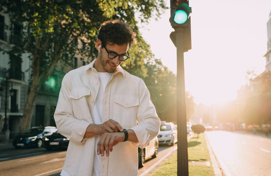 stylish businessman checks his smartwatch while walking through the city at sunset. Focused and connected, he manages his time efficiently, embracing technology for productivity and work-life balance.